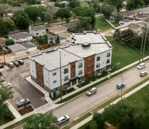 A large apartment building with a parking lot in front.