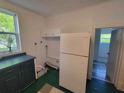 A white fridge in a kitchen with a black counter and cabinets.