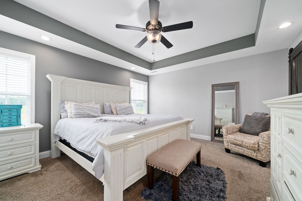 a white bedroom with a large bed and a ceiling fan