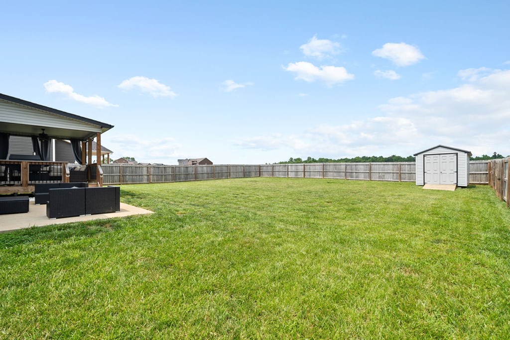 a backyard with a fence and a yard with a barbecue grill