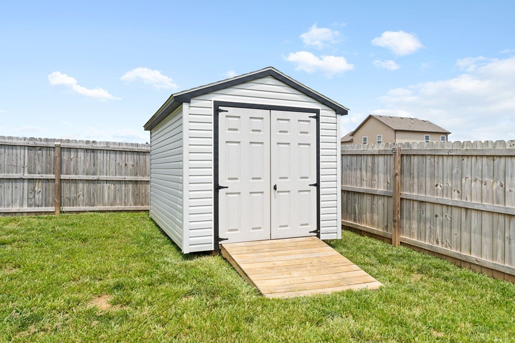 a shed in a backyard with a wooden deck and a fence