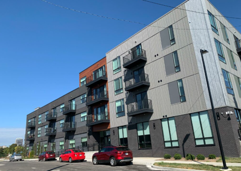 A modern apartment building with cars parked in front.
