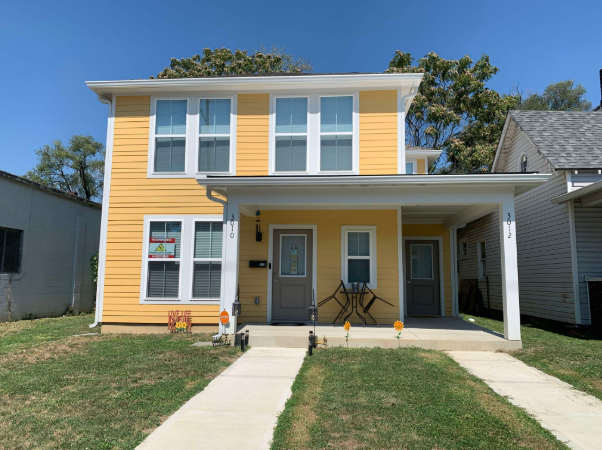 A yellow house with a grey door and windows.