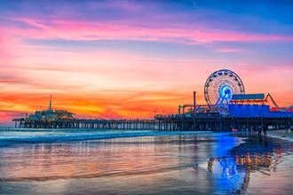 a colorful sunset over the beach and a ferris wheel