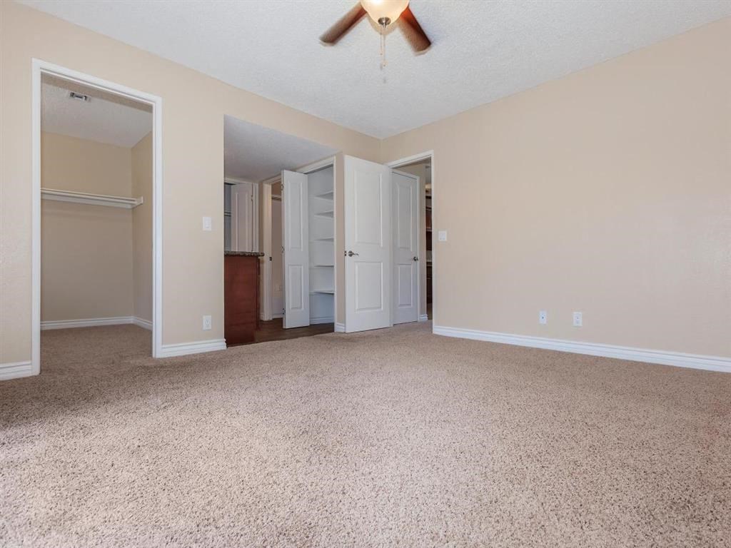 an empty living room with a ceiling fan and a closet