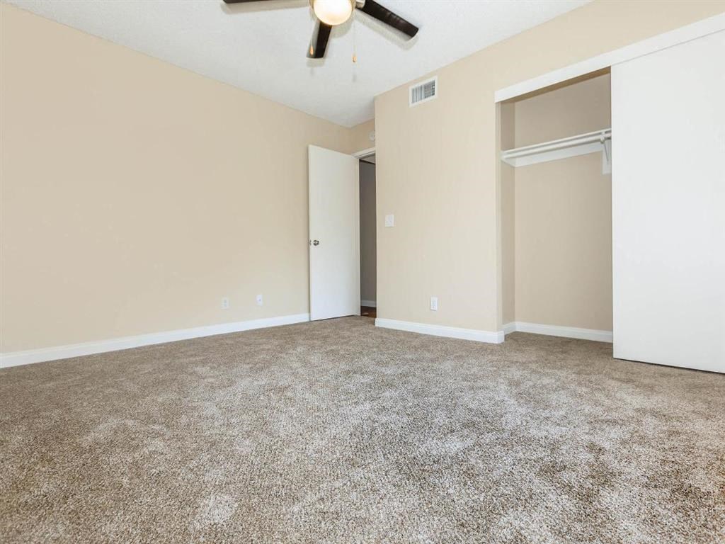 an empty living room with a ceiling fan and a closet