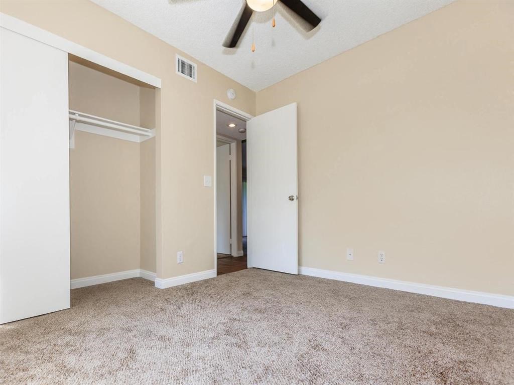 an empty living room with a ceiling fan and a closet