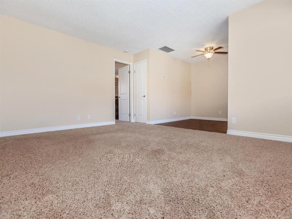 an empty carpeted living room with a ceiling fan