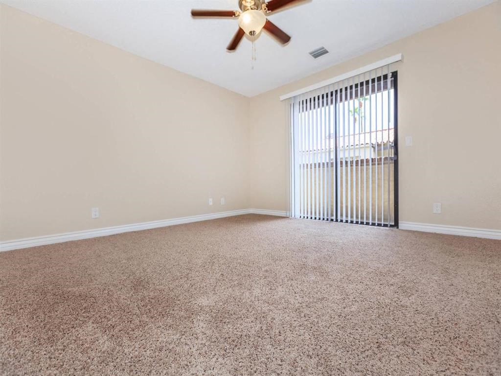 an empty living room with a window and a ceiling fan