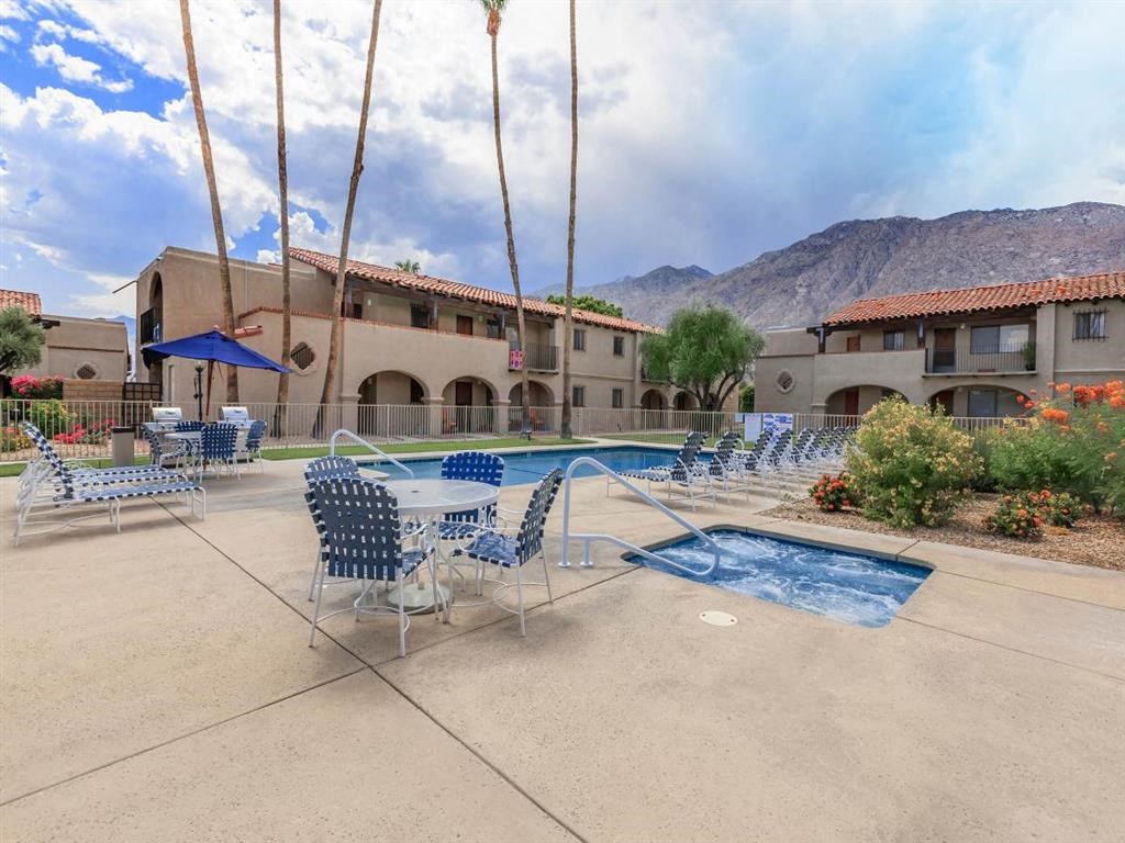 a swimming pool and patio with chairs and tables