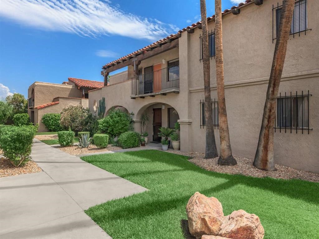 a sidewalk in front of a building with grass and trees