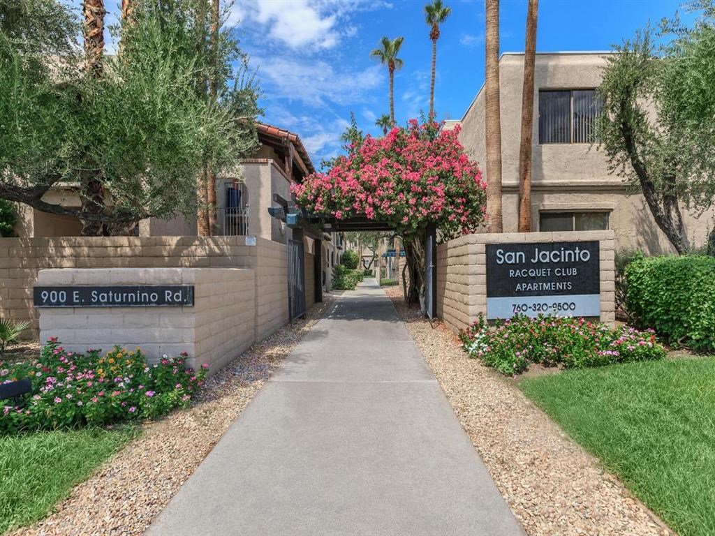 a sidewalk in front of a building with a sign apartments