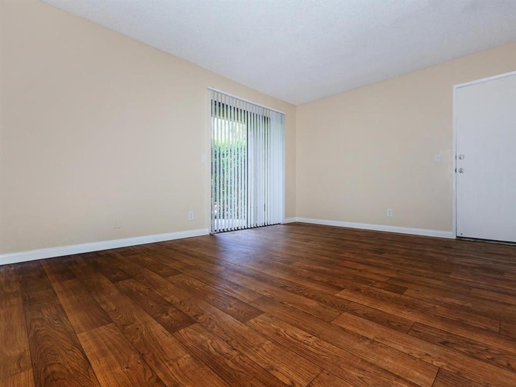 an empty living room with wood floors and a sliding glass door
