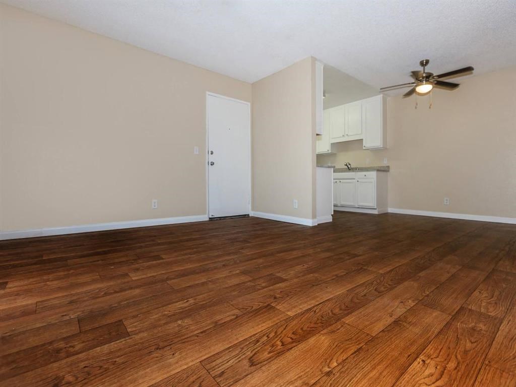 an empty living room with wood floors and a ceiling fan