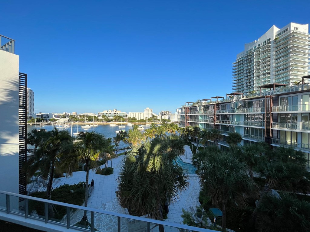 a view of the water from a balcony with palm trees