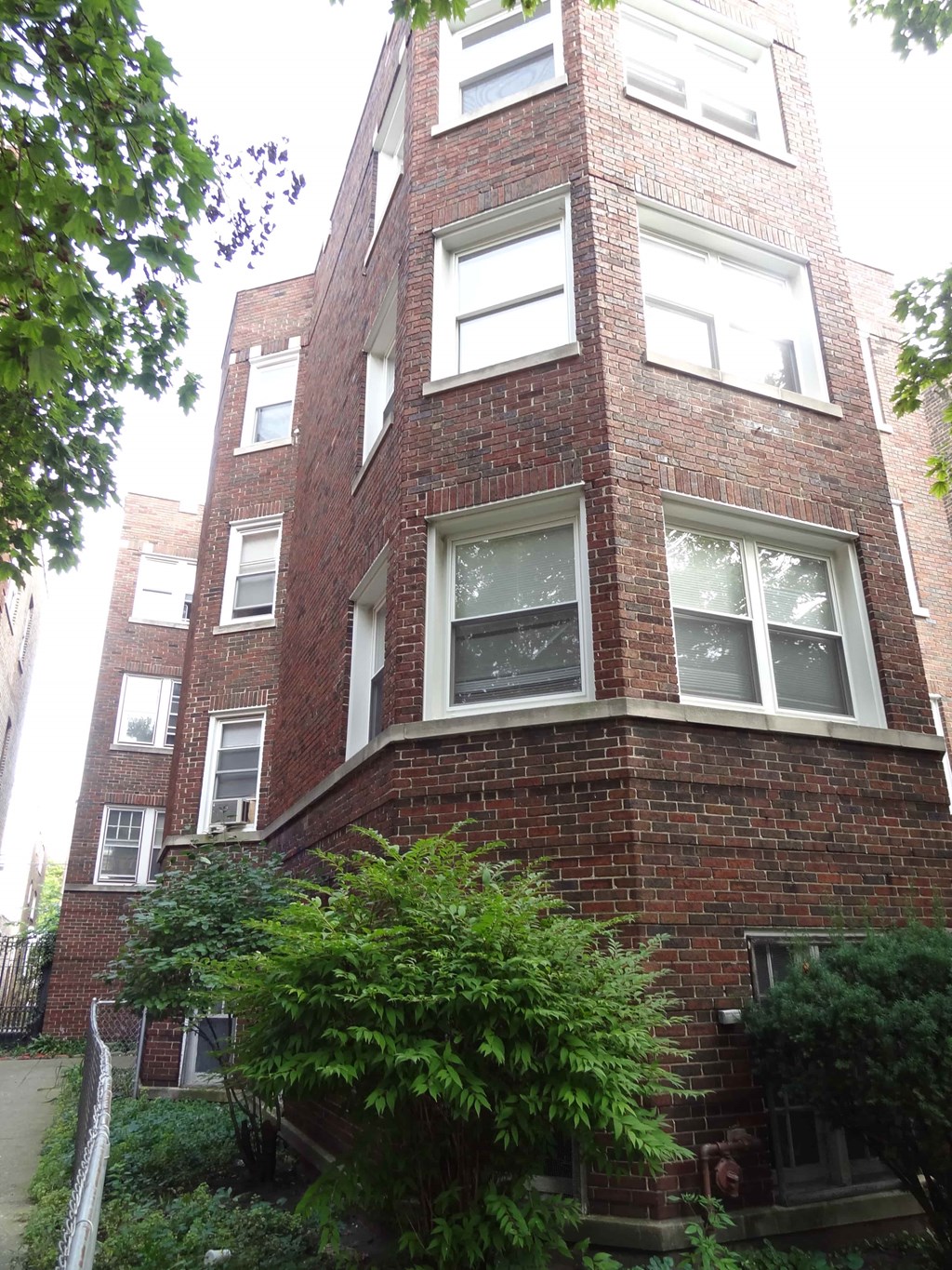 a red brick building with many windows and a tree in front