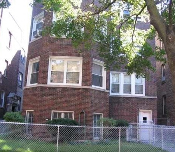 a brick house with a fence in front of it