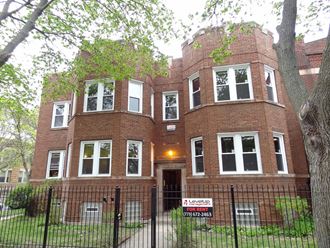 a large brick building with a yard and a fence in front of it