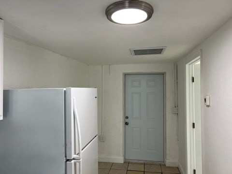 A white refrigerator in a kitchen with a white door.