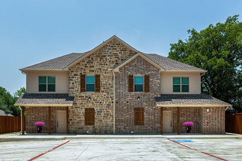 an empty parking lot in front of a brick house