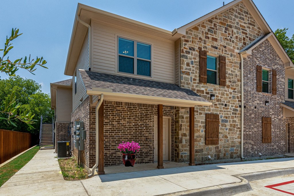 a brick house with a porch and a flower pot on the sidewalk