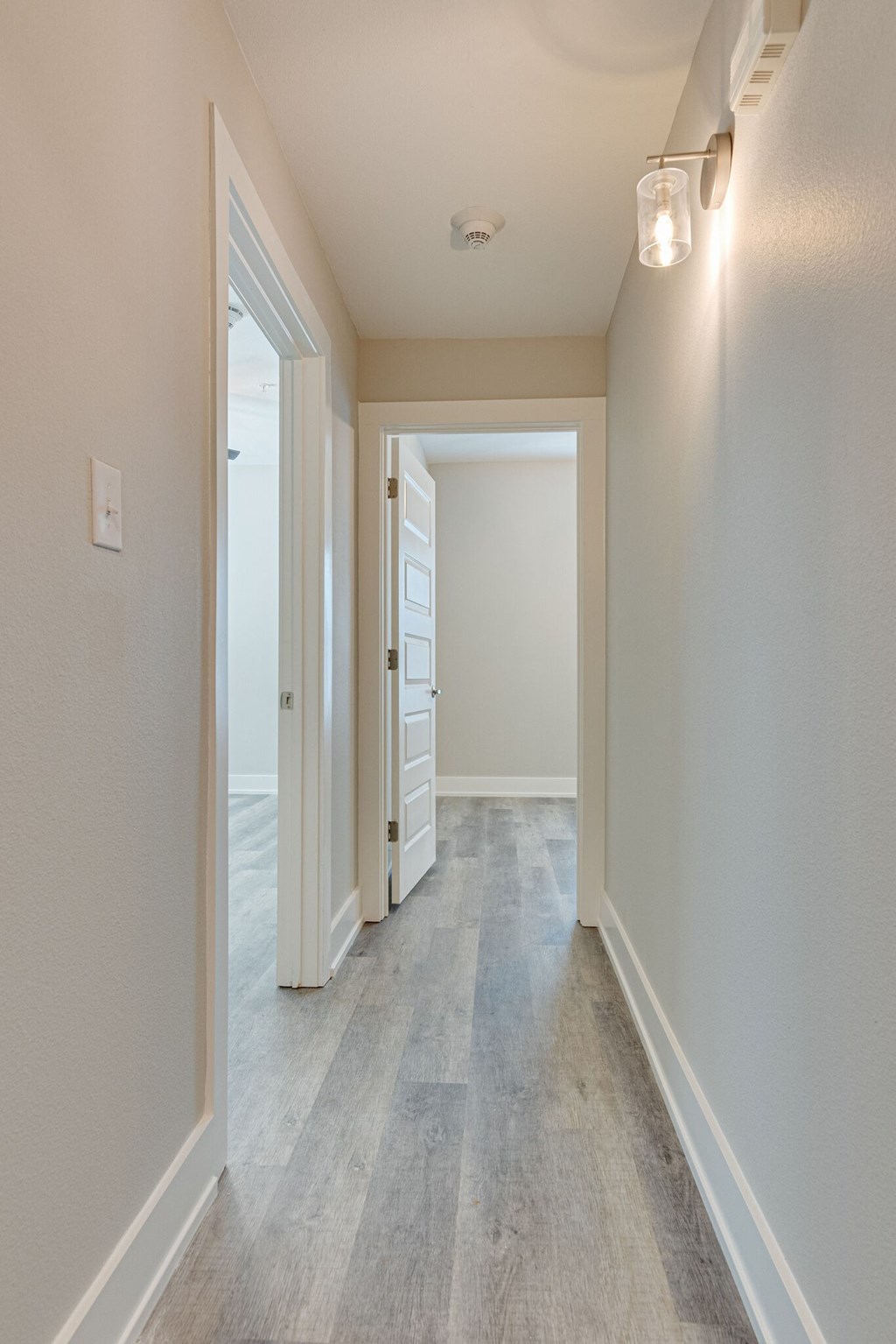 an empty living room and hallway with white walls and white doorways