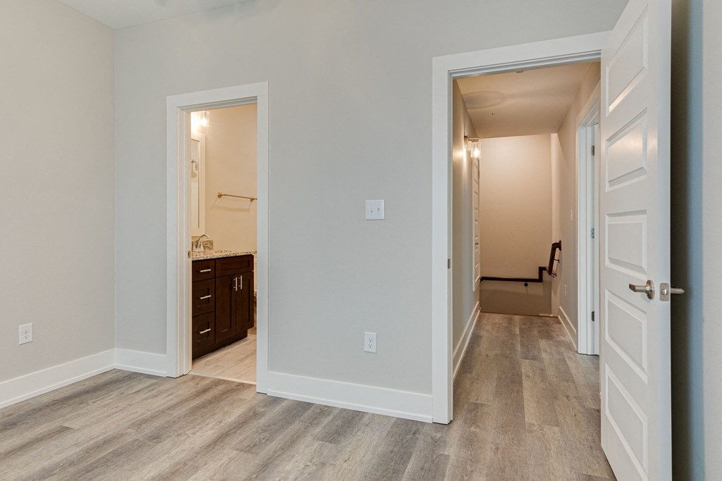 an empty living room with a hallway to a bedroom and a bathroom