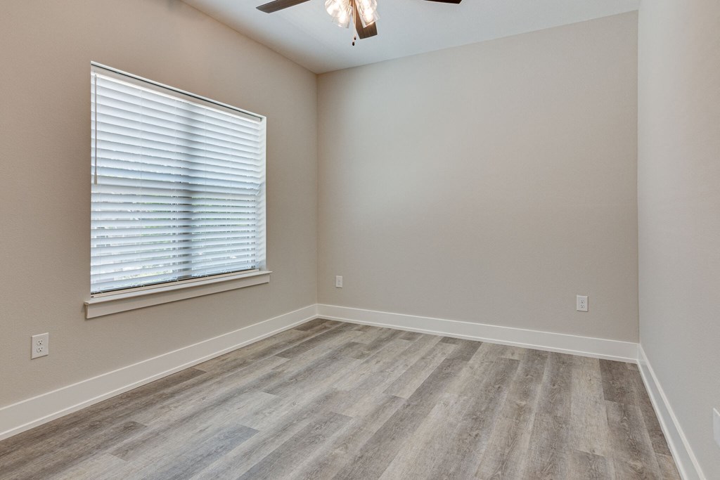 an empty bedroom with wood floors and a window