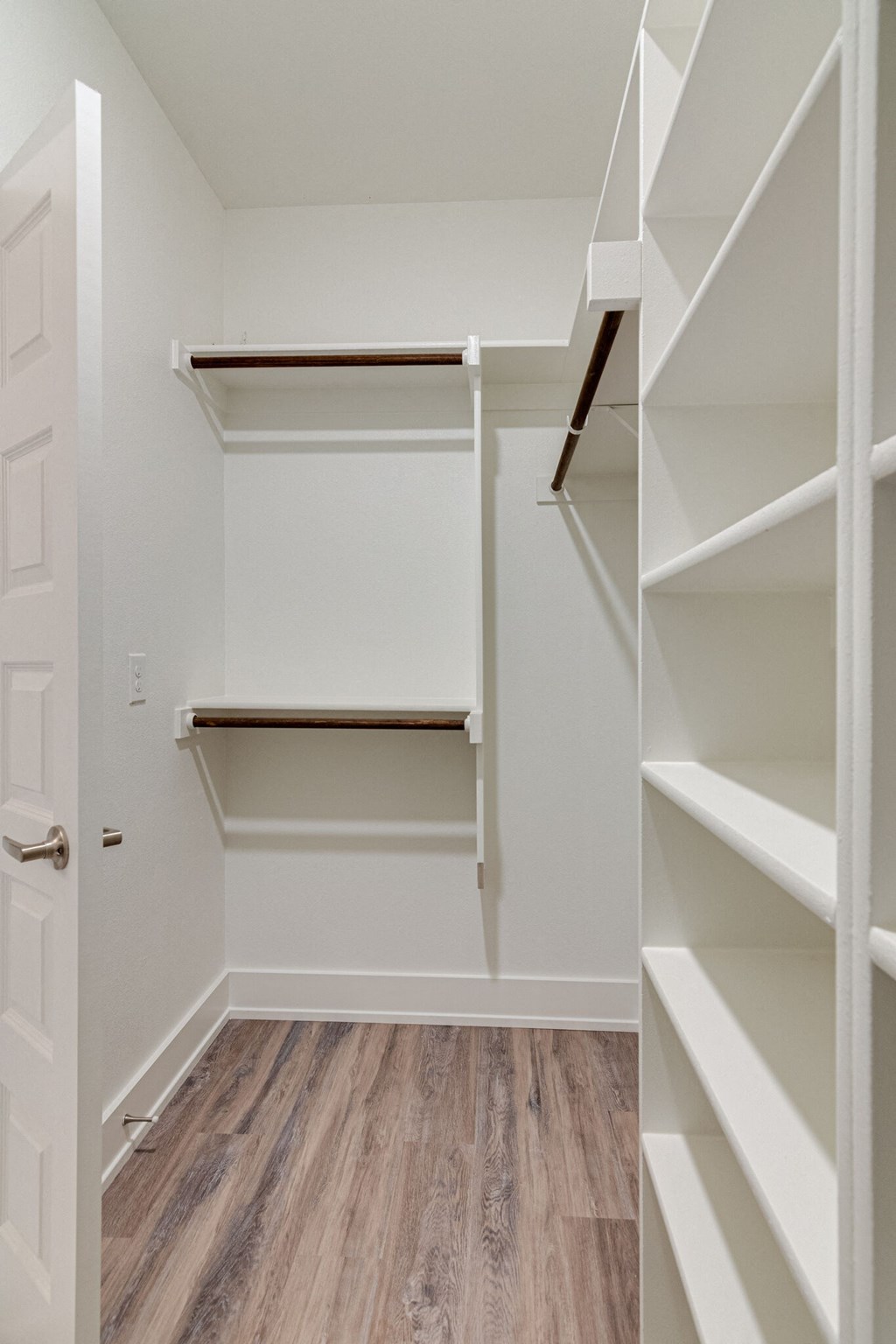 a walk in closet with shelves and a door