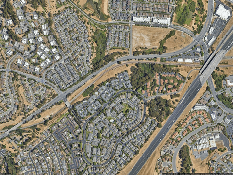 A satellite image of a residential area with a road running through it.