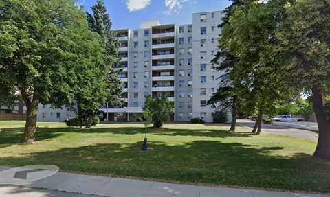 A large white apartment building with a green lawn in front.