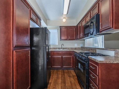 a kitchen with wooden cabinets and a black refrigerator