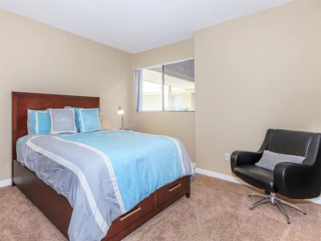 a bedroom with a bed and a chair and a window