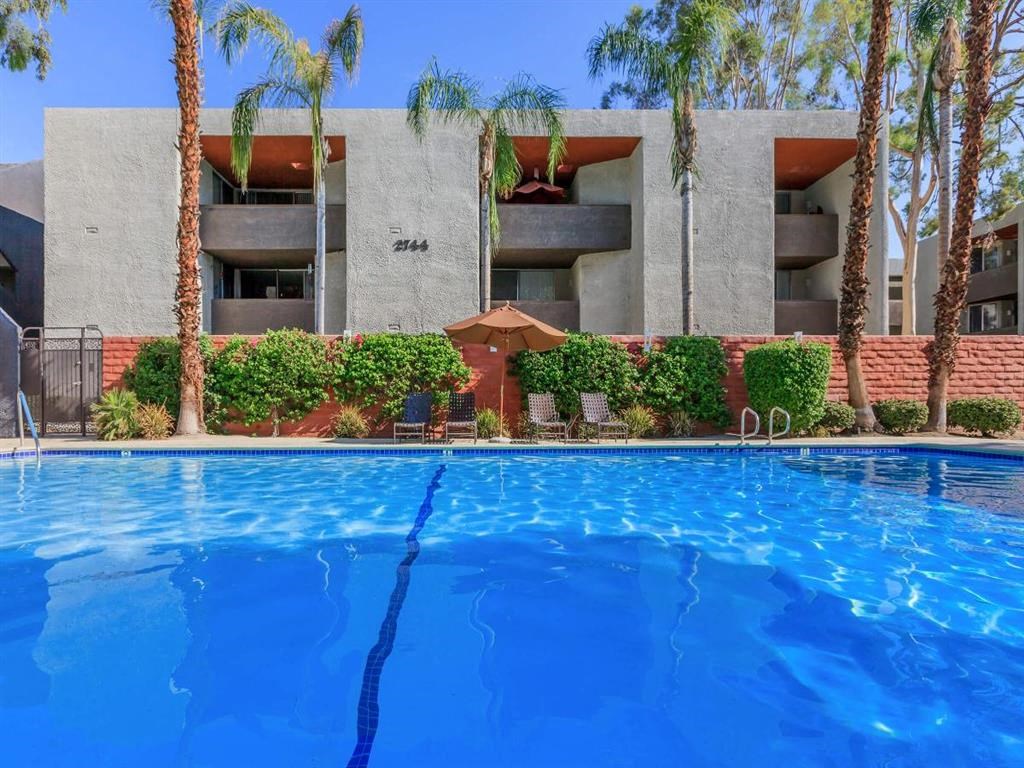a large swimming pool in front of a building with palm trees