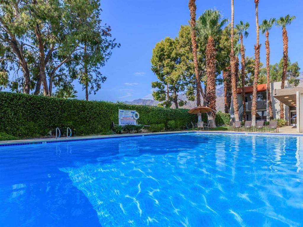 a large pool with palm trees and a building in the background