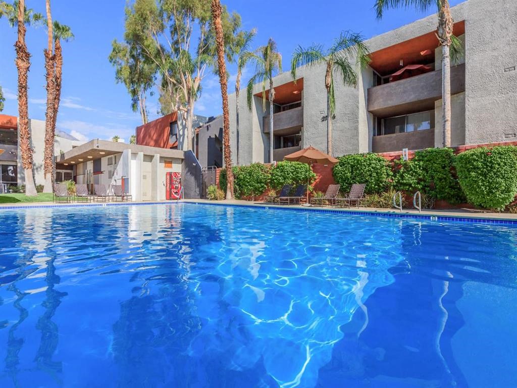 a large swimming pool in front of a hotel with palm trees