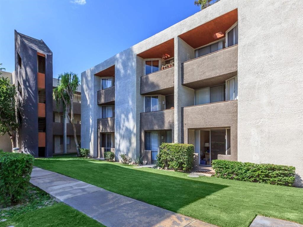 an apartment building with green grass and a sidewalk