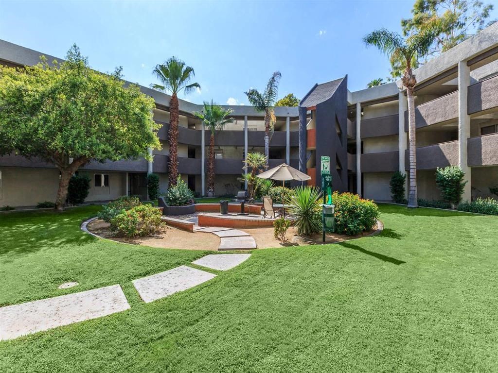a grassy area with a fountain in front of an apartment building