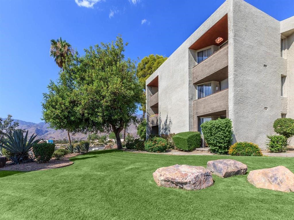 a garden in front of a building with grass and rocks