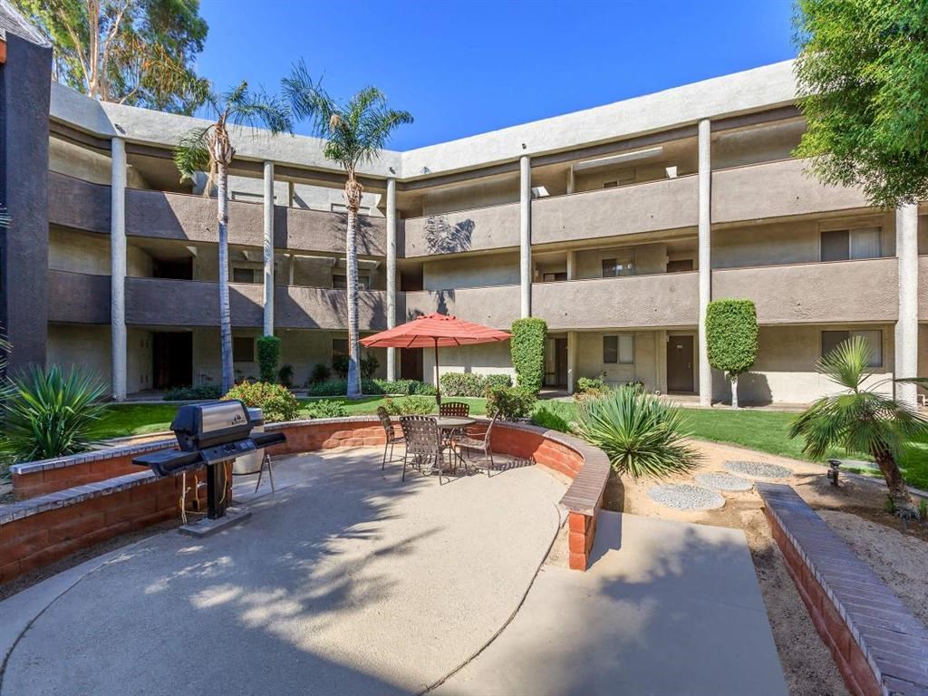 a courtyard with a barbecue grill in front of a building