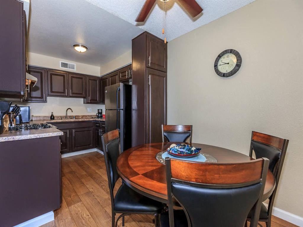 a dining room with a table and a kitchen with a refrigerator