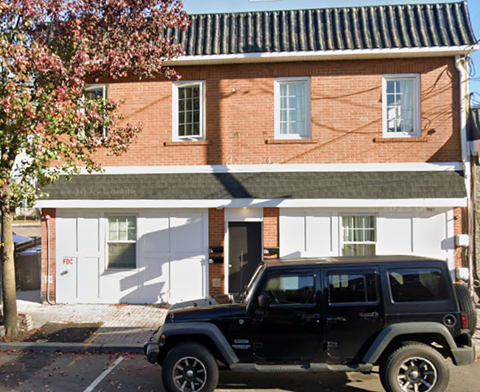 A black jeep is parked in front of a red brick house.