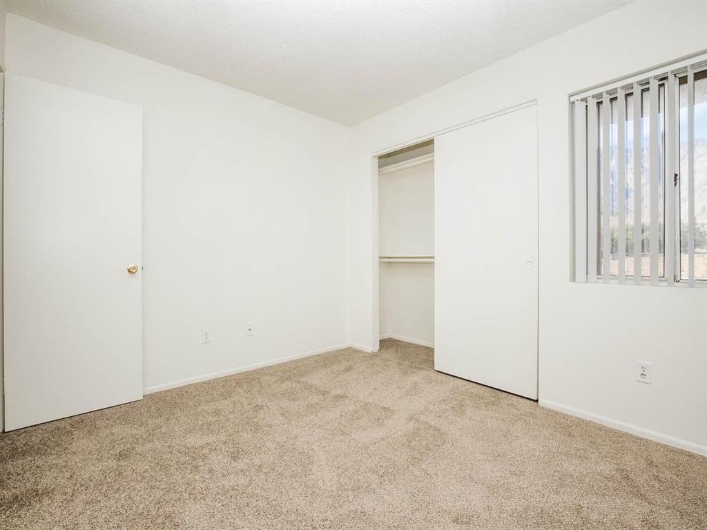 an empty bedroom with a closet and a window