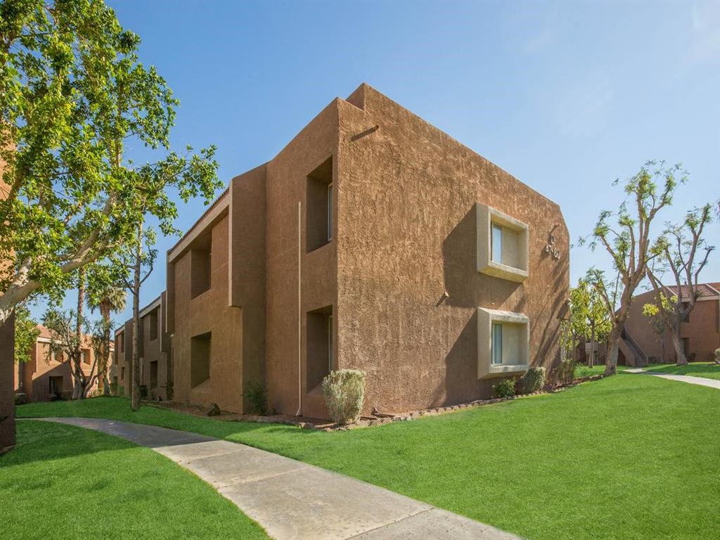 the side of a building with grass and a sidewalk