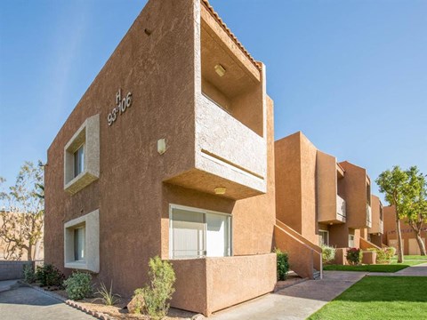 a brown building with a sidewalk and grass in front of it