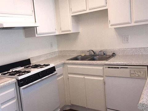 a kitchen with a stove sink and white cabinets