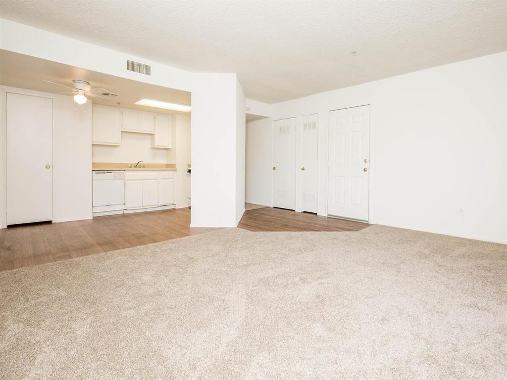 an empty living room and kitchen with white walls
