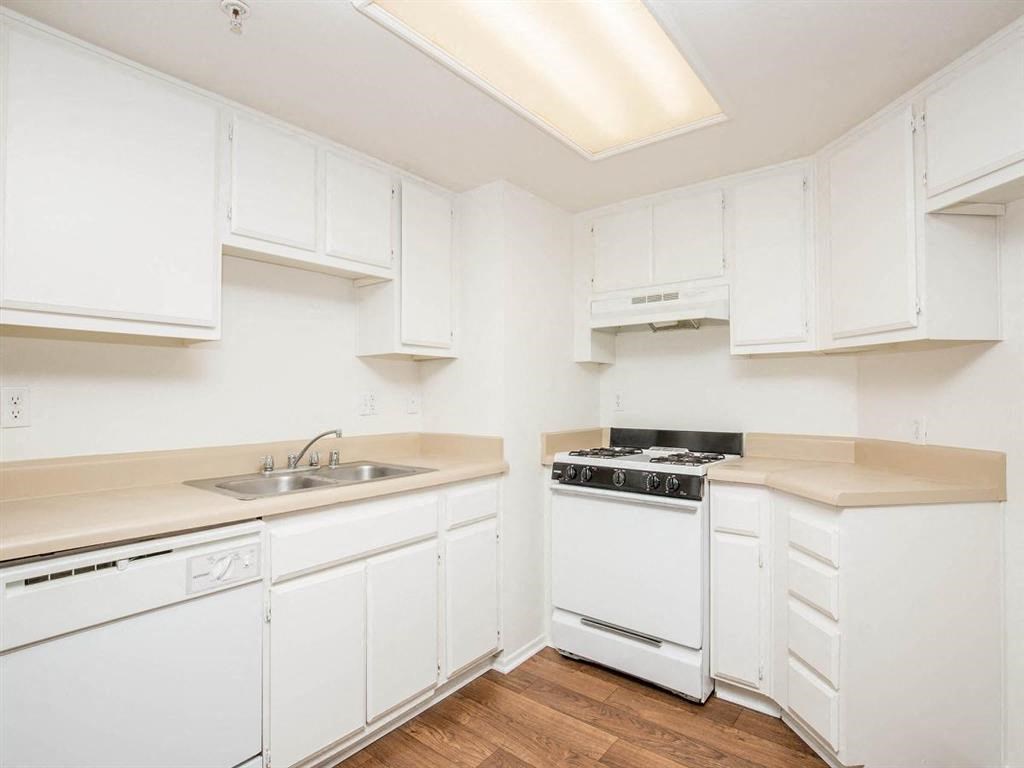 a kitchen with white cabinets and a sink and a stove
