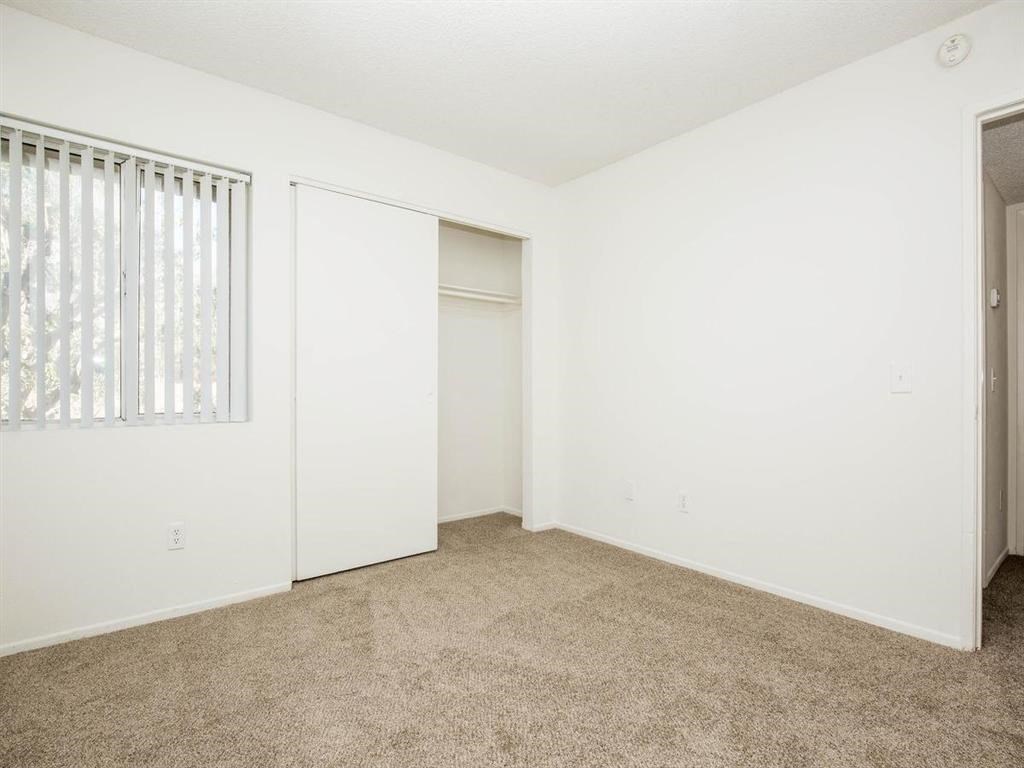 an empty living room with a window and a closet