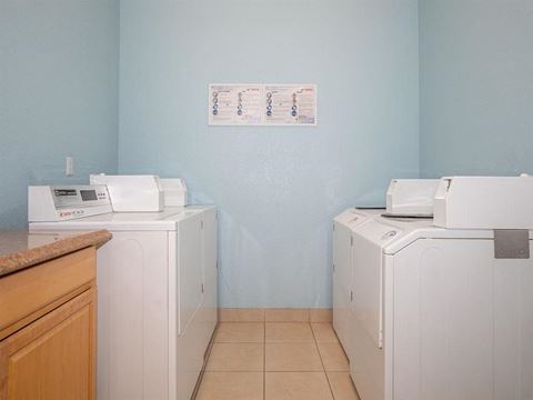 three washes and two dryers in a laundry room with a counter